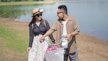 happy young asian couple walking bicycle in park in summer photo