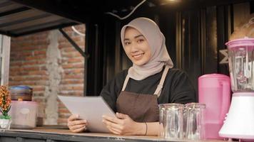 hermosa camarera asiática sonriente que lleva la lista del menú en el contenedor de la cabina del café foto