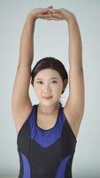 mujer asiática practicando yoga en casa haciendo movimiento de mano caliente foto