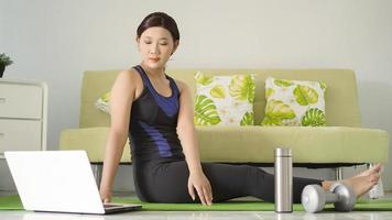 young woman practicing yoga looking for ideas from laptop at home photo