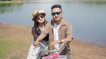 happy young asian couple walking bicycle in park in summer photo