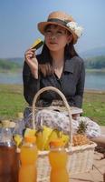 joven asiática comiendo sandía mientras está de vacaciones junto al lago foto