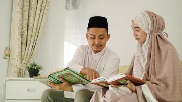 Muslim husband helping his wife read the Quran photo