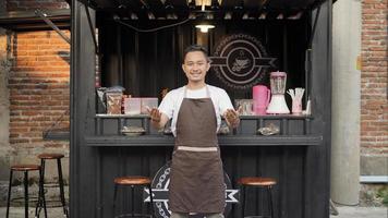 Asian man barista attracts customer's attention in container themed cafe