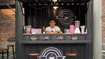 asian man in apron guarding container angkringan photo