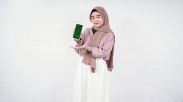 Young woman in hijab showing mobile phone screen isolated on white background photo