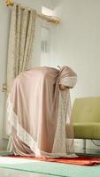 Muslim women pray with a bowing motion while wearing a mukenah photo