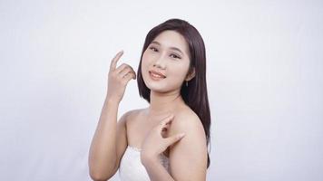 Chica asiática maquillada mostrando su cara sonriente aislada de fondo blanco foto