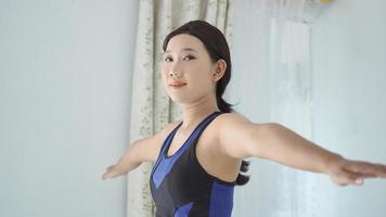 asian woman practicing yoga at home warming up hand gesture photo