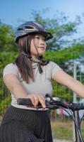 joven asiática disfrutando del ciclismo cuando se detuvo en la mañana de verano foto