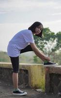 Young Asian woman has prepare her shoes before running and jogging in the morning photo
