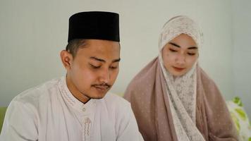 Asian Muslim couple praying together at home photo