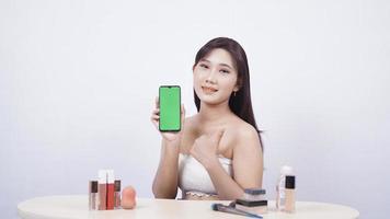 hermoso maquillaje asiático que muestra la pantalla del teléfono inteligente ok gesto aislado sobre fondo blanco foto