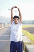 young asian man having streaching before jogging in the morning photo