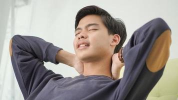 tired asian young man closing his eyes looking for ideas at home photo