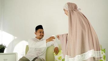 Muslim woman gives her husband a glass of drink photo