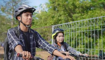 joven pareja asiática andar en bicicleta juntos ir a trabajar foto