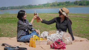 two young asian women cheering drinking while vacationing by the lake photo