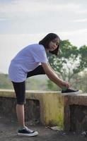 Young Asian woman has prepare her shoes before running and jogging in the morning photo