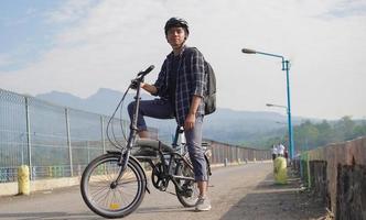joven asiático con mochila descansando después de andar en bicicleta foto