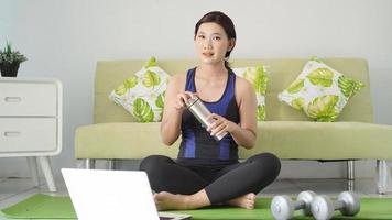 asian woman finished yoga resting at home looking at her laptop screen photo