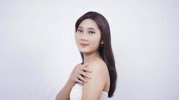 Chica asiática con maquillaje sonriendo dulcemente mano lateral hombro aislado sobre fondo blanco. foto
