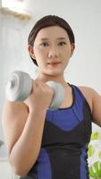 asian woman lifting full arm barbell at home