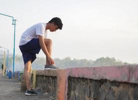 young asian man prepare his shoes before jogging in the morning photo