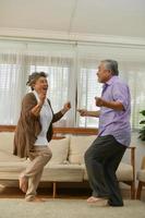 Spending time together at home, an elderly Asian couple having fun dancing in the living room. photo