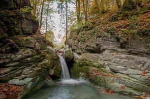 Waterfall of river water in the forest in autumn photo