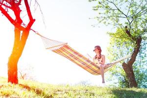 Woman sitting on a hammock reads a book photo