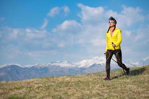 Girl with yellow down jacket strolls in the mountains photo