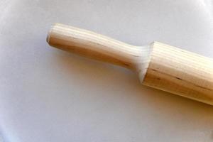 Wooden rolling pin for dough on a white background photo