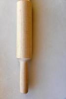 Wooden rolling pin for dough on a white background photo