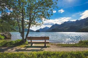 Wooden tourist bench in front of a mountain lake photo