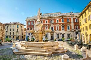 Brescia, Italy, September 11, 2019 Fountain, street restaurant tables and Credito Agrario Bresciano bank photo