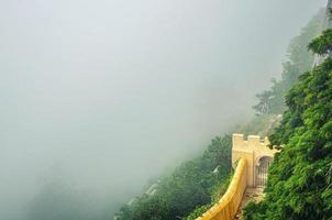 Sintra, Portugal - June 14, 2017 defense wall with gate of Pena Palace on steep slope of mountain with green forest in fog, Palacio Nacional da Pena photo