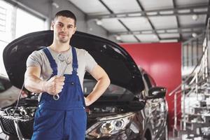 Hands of car mechanic with wrench in garage photo