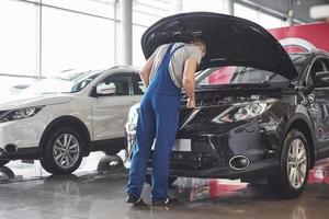 Imagen que muestra un trabajador de servicio de coche musculoso reparando el vehículo foto