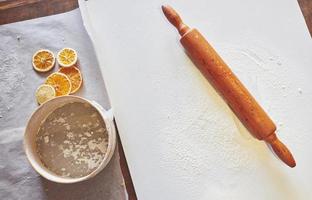 Wooden rolling pin with white wheat flour on the table. top view photo