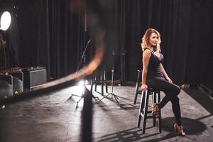 Young sexy woman in black sitting on chair. Retro style film colors effect photo