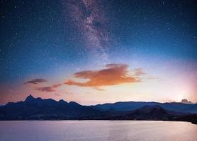 magnificent panorama of sunrise over the sea. Vibrant night sky with stars and nebula and galaxy. Deep sky astrophoto