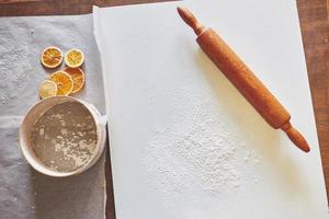 Wooden rolling pin with white wheat flour on the table. top view photo