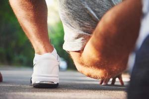 correr a campo traviesa al aire libre en el concepto de sol de verano para hacer ejercicio, estar en forma y un estilo de vida saludable. cerca de los pies de un hombre corriendo en la hierba foto