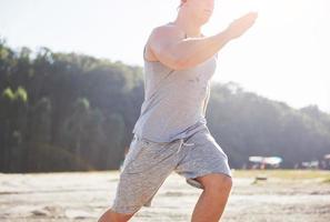 atleta fitness hombre trotando en la naturaleza durante la puesta de sol. persona corriendo ejercitándose viviendo un estilo de vida activo entrenando cardio en verano en ropa deportiva y zapatos.