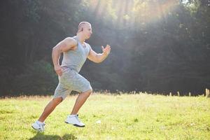 atleta fitness hombre trotando en la naturaleza durante la puesta de sol. persona corriendo ejercitándose viviendo un estilo de vida activo entrenando cardio en verano en ropa deportiva y zapatos.