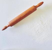 Wooden rolling pin with white wheat flour on the table. top view photo