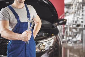 Hands of car mechanic with wrench in garage photo