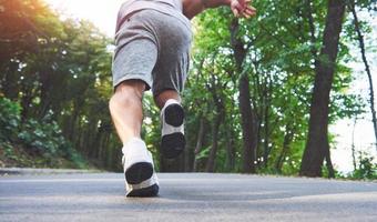 carrera a campo traviesa al aire libre en concepto de ejercicio, fitness y estilo de vida saludable. cerca de los pies del joven corredor corriendo por la carretera en el parque foto