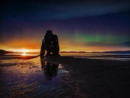 starry sky and northern lights in a spectacular rock in the sea on the Northern coast of Iceland. Legends say it is a petrified troll photo